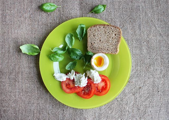 Assiette d'aliments sains : mâche, tomate, œuf et pain complet.